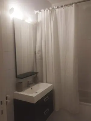 a bathroom with a sink and a white shower curtain at Cocon chaleureux proche commerces et centre in Marrakech