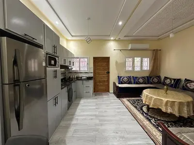 a kitchen with a table and a refrigerator at Studio tranquille dans le village touristique in Marrakech