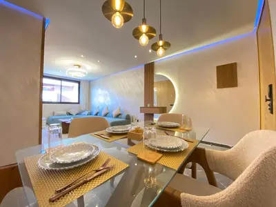a dining room and living room with a table and chairs at Chic garden & grand balcon in Marrakech