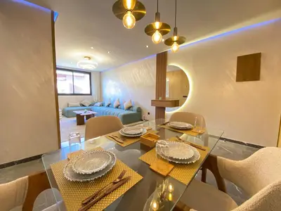 a dining room and living room with a table and chairs at Chic garden & grand balcon in Marrakech