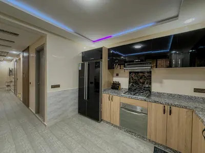 a kitchen with wooden cabinets and a black refrigerator at Essalmi Duplex Apartment in Marrakech in Marrakech