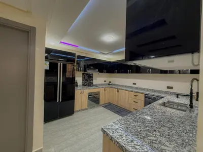 a kitchen with wooden cabinets and a black refrigerator at Essalmi Duplex Apartment in Marrakech in Marrakech