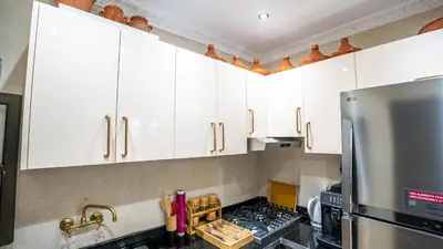 a kitchen with white cabinets and a stainless steel refrigerator at Riad Le Soleil Rouge in Marrakech