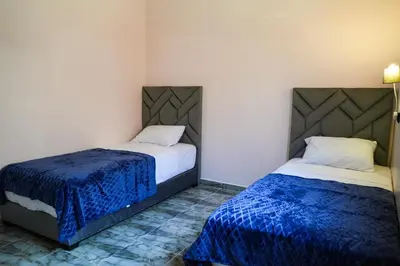 two beds in a small room with blue sheets at Appartement Moderne a Marrakech - 2 Chambres, Salon et Cuisine Equipee in Marrakech