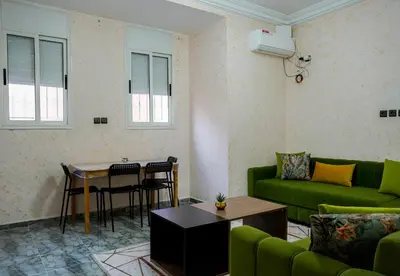 a living room with a green couch and a table at Appartement Moderne a Marrakech - 2 Chambres, Salon et Cuisine Equipee in Marrakech