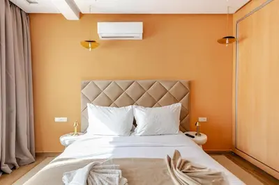 a bedroom with a large white bed with orange walls at Modern & Refined Apartment Majorelle Downtown in Marrakech