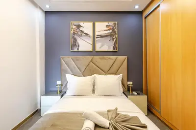 a bedroom with a large bed and two paintings on the wall at Modern & Refined Apartment Majorelle Downtown in Marrakech