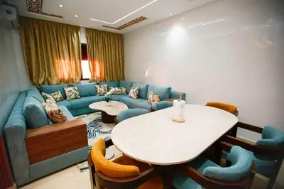 a living room with a blue couch and a table at Bel Appartement 2 Chambres Confort et Emplacement Idéal in Marrakech