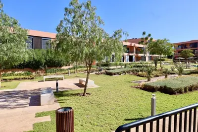 a park with a bench and a tree and a building at Noria Golf Marrakeck 2 chambres jardin in Marrakech