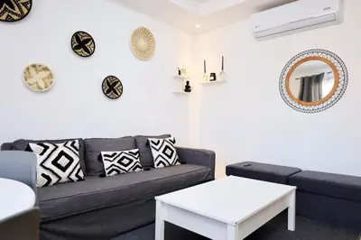 a living room with a couch and clocks on the wall at Noria Golf Marrakeck 2 chambres jardin in Marrakech