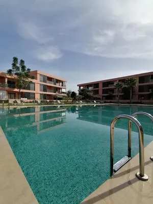 a swimming pool with blue water in front of a building at Noria Golf Marrakeck 2 chambres jardin in Marrakech