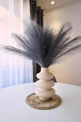 a white vase with black feathers on a table at Noria Golf Marrakeck 2 chambres jardin in Marrakech