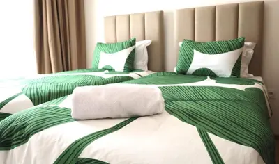two beds with green and white sheets and pillows at Marrakech Noria Golf, cosy appartement 2 chambres in Marrakech