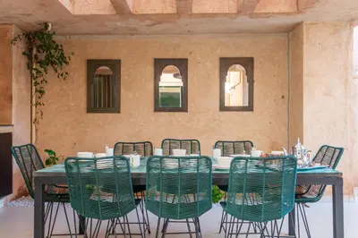 a table with green chairs around it in a patio at Luxury Villa Private Pool & Golf View 7 min to center in Marrakech