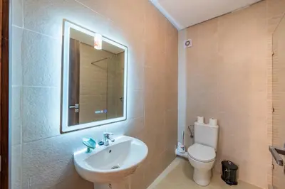 a bathroom with a sink and a toilet and a mirror at AFCON Stay Gueliz 2BR & Pool, Parking & Wi-Fi in Marrakech