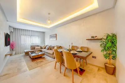 a living room with a table and a couch at AFCON Stay Gueliz 2BR & Pool, Parking & Wi-Fi in Marrakech