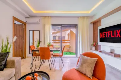 a living room with a table and chairs and a television at Cozy Gueliz Apartment , Access to Pool , Central Location in Marrakech