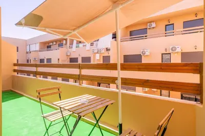 a balcony of a building with a table and chairs at Cozy Gueliz Apartment , Access to Pool , Central Location in Marrakech