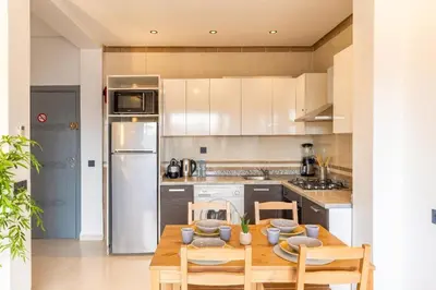 a kitchen with a table and chairs and a refrigerator at Cozy 1BR Apt Fast WiFi Peaceful Spot n Center of Gueliz Marrakech in Marrakech