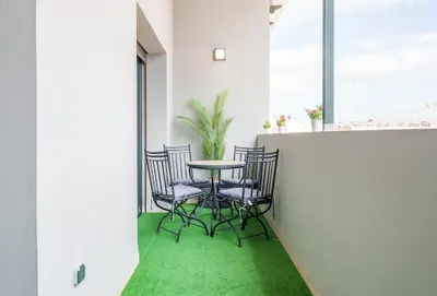 a table and chairs on a balcony with green carpet at Cozy 1BR Apt Fast WiFi Peaceful Spot n Center of Gueliz Marrakech in Marrakech