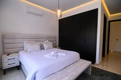 a bedroom with a large white bed and a black cabinet at Villa Marrakech - Argan Golf - Swimming Pool in Marrakech