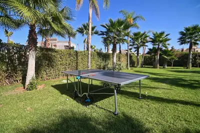 a ping pong table in a yard with palm trees at Villa Marrakech - Argan Golf - Swimming Pool in Marrakech