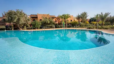 a large swimming pool with blue water at Appartement cosy, calme, détente, piscines, jardins in Marrakech
