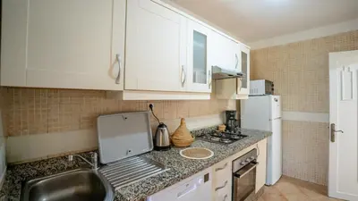 a small kitchen with white cabinets and a sink at Appartement cosy, calme, détente, piscines, jardins in Marrakech