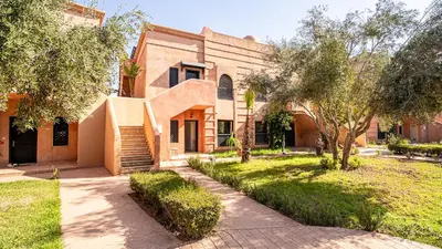 a building with trees and a sidewalk in front of it at Appartement cosy, calme, détente, piscines, jardins in Marrakech