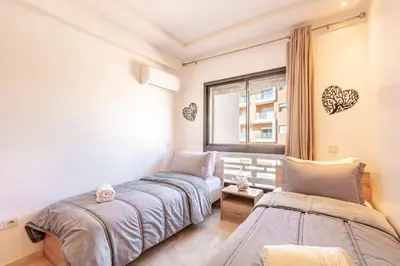 two beds in a room with a window at Appartement Chic & Cosy Hivernage in Marrakech