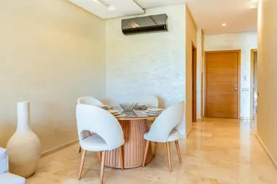 a dining room with a table and white chairs at Spacious 2BR , Pool & Garden , Golf View , Fast WiFi in Marrakech