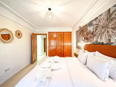 a bedroom with a large white bed with a chandelier at Escapade Gueliz - Central & parking Privé in Marrakech