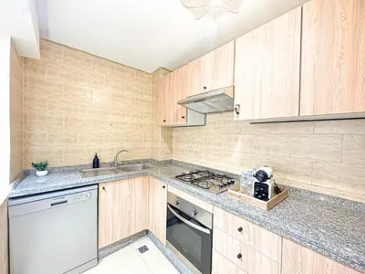 a kitchen with wooden cabinets and a sink and a stove at Escapade Gueliz - Central & parking Privé in Marrakech