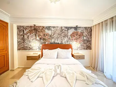 a bedroom with a bed with white sheets and a wallpaper at Escapade Gueliz - Central & parking Privé in Marrakech