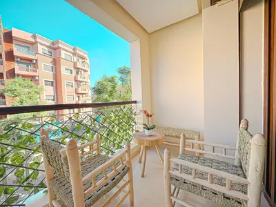 a balcony with chairs and a table and a view of a building at Escapade Gueliz - Central & parking Privé in Marrakech
