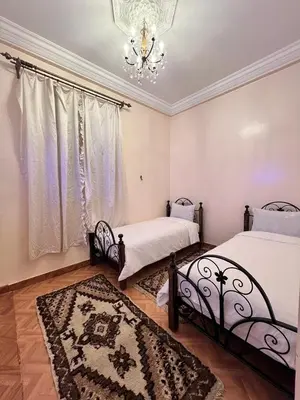 a bedroom with two beds and a chandelier at Tumsilt in Marrakech