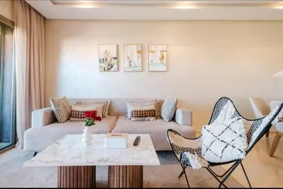 a living room with a couch and a table and chairs at Appartement 2 chambres a PRESTIGIA piscine in Marrakech