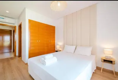 a bedroom with a large white bed with a wooden headboard at Appartement 2 chambres a PRESTIGIA piscine in Marrakech