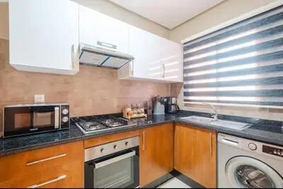 a kitchen with a stove top oven next to a microwave at Appartement 2 chambres a PRESTIGIA piscine in Marrakech