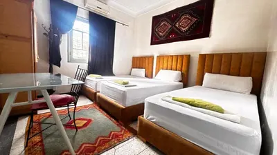 a bedroom with two beds and a table and a desk at Les appartements de la Koutoubia in Marrakech