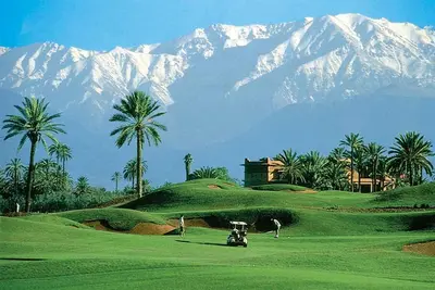 a golf course with a snow covered mountain in the background at Amelkis Golf Villa Prestige Habaïta Marrakech in Marrakech