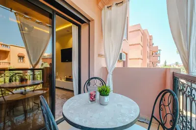 a balcony with a table and chairs on a balcony at Appartement Standing Marrakech Caricia in Marrakech