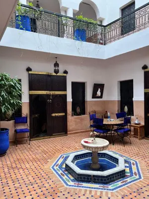 a large room with a table and chairs and a fountain at RIAD Dar Aïlen Médina in Marrakech