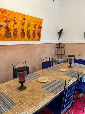 a table with chairs and a painting on the wall at RIAD Dar Aïlen Médina in Marrakech