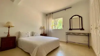 a white bedroom with a bed and a window at Grand duplex Palmeraie in Marrakech