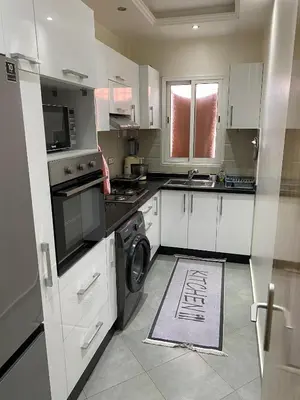 a kitchen with white cabinets and a washer and dryer at Charmante moderne Wohnung in der Nähe des Flughafens in Marrakech