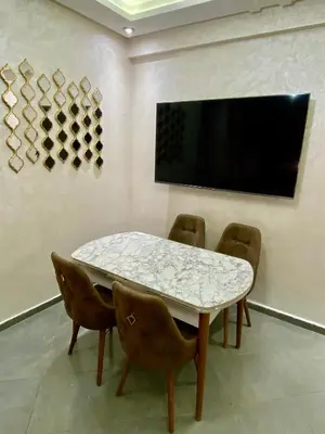 a dining room with a table and chairs and a tv at Charmante moderne Wohnung in der Nähe des Flughafens in Marrakech