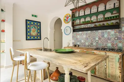 a kitchen with a wooden table and some chairs at Riad Koubba in Marrakech