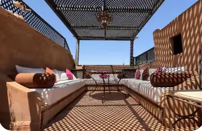 a screened in porch with two beds and a table at Welcome to your Stylish Atlas View Apartment in Marrakech