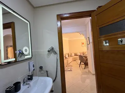 a bathroom with a sink and a mirror and a living room at Appartement de luxe dans le centre de Marrakech in Marrakech